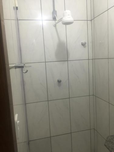 a bathroom with a shower with white tiles at Pousada Tilu in Aparecida