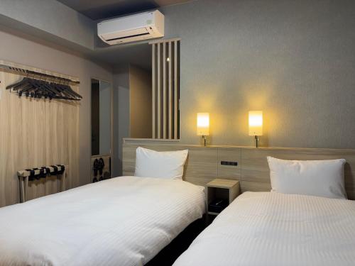 two beds in a hotel room with white sheets at Hotel Route Inn Okayama Maniwa in Maniwa
