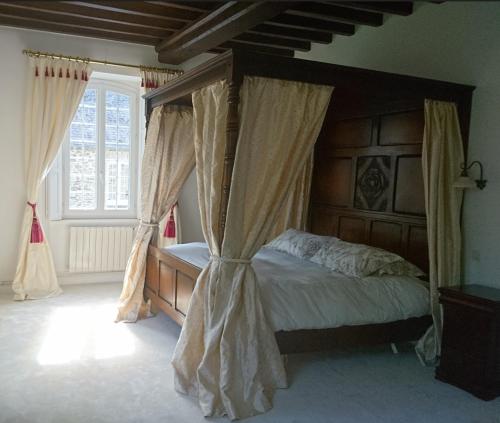 a bedroom with a canopy bed with curtains at Moulin des Rondelles in Cerisy-la-Forêt