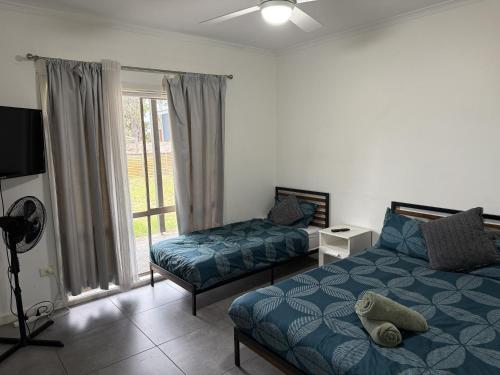 a bedroom with two beds and a tv and a window at Roseneath Holiday Park in Meerlieu