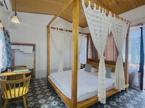 a bedroom with a canopy bed and a desk at Bình An Village in Vĩnh Long