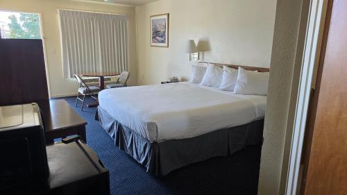 a hotel room with a large bed and a chair at Terrace Inn and Suites in El Cerrito