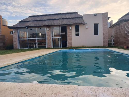 a swimming pool in front of a house at Casa 3 dormitorios en Barrio Privado con vigilancia en Haras el Terraplen, General Rodriguez, con Pileta, quincho, parrilla in General Rodríguez
