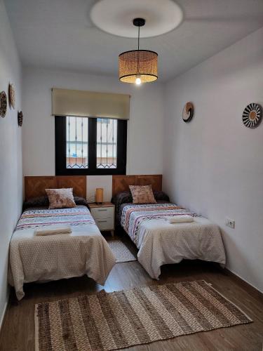 a bedroom with two beds and a chandelier at Casa Rural Feymar in Peraleda de San Román