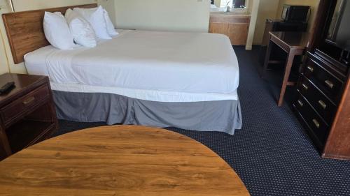 a hotel room with two beds and a wooden table at Terrace Inn and Suites in El Cerrito