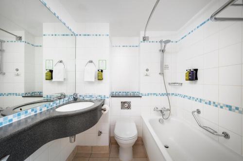 a bathroom with a sink and a tub and a toilet at Holiday Inn Norwich, Ipswich Road by IHG in Norwich