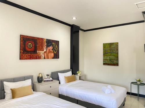 deux lits dans une chambre avec des tableaux au mur dans l'établissement Wink City 4th Patong, à Patong Beach