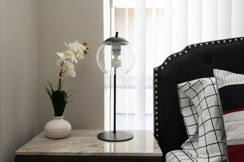 a table with a lamp and a vase with flowers on it at Stylish Hollywood Hideaway 1Bed Rooftop Pool with Iconic View D in Los Angeles