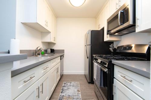 a kitchen with white cabinets and a black refrigerator at Stylish Hollywood Hideaway 1Bed Rooftop Pool with Iconic View D in Los Angeles