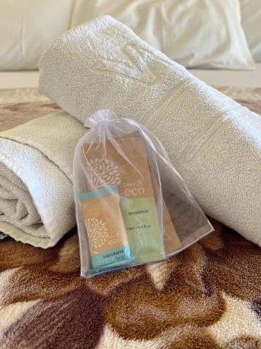 a bottle of soap and towels on a bed at Pousada Hostel Shalom in Rio das Ostras