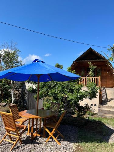 a table and chairs with a blue umbrella at Munduk Nature Lodge in Munduk