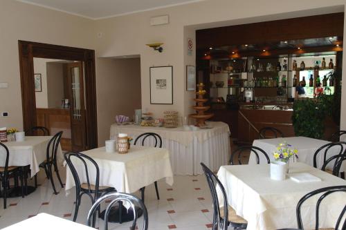 un restaurante con mesas y sillas blancas y un bar en Hotel Armando' s, en Sulmona