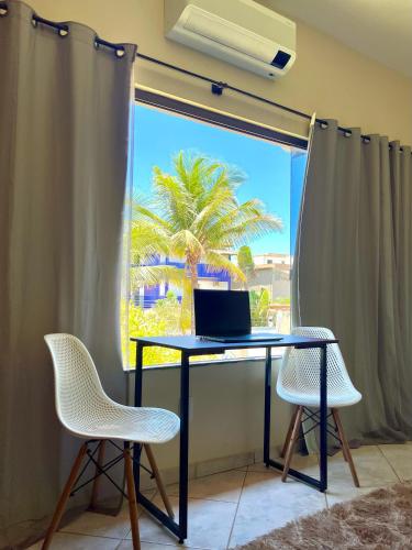 a desk with a laptop on it in front of a window at Pousada Hostel Shalom in Rio das Ostras