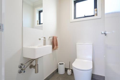 a white bathroom with a toilet and a sink at Two bedrooms family house in Coles Bay with direct access to the Swan River! in Coles Bay