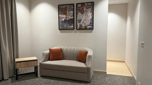 a chair with two orange pillows sitting in a room at فندق آرام النسيم in Ash Shishah