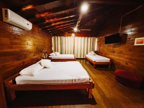a bedroom with two beds in a wooden room at Casa Hotel La Cherna in Bahía Solano