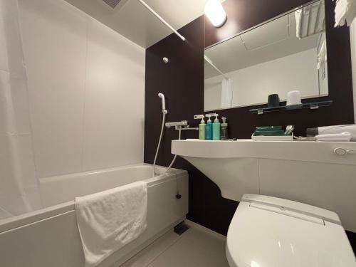 a bathroom with a white toilet and a sink and a tub at Hotel Route Inn Okayama Maniwa in Maniwa