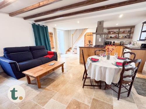 un salon avec une table et un canapé bleu dans l'établissement Tranquiloue - Maison paisible à 7min du PuyduFou, aux Épesses