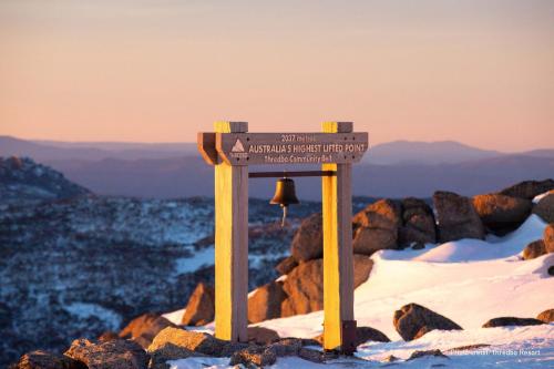 a sign on top of a mountain with a bell at Stratton Summit 4 in Jindabyne