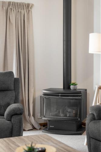 a living room with a fireplace and two chairs at Moana Hideaway - 3BR, BBQ, Parking in Moana