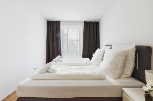 a white bed with white pillows and a window at Symphony Apartments Vienna - Garden, Terrace and Grill in Vienna