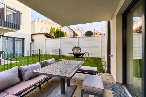 a patio with a couch and a wooden table at Symphony Apartments Vienna - Garden, Terrace and Grill in Vienna