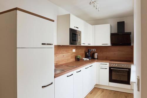 a white kitchen with white cabinets and a refrigerator at Symphony Apartments Vienna - Garden, Terrace and Grill in Vienna