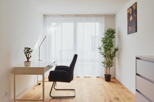 a desk and a chair in a room with a window at Symphony Apartments Vienna - Garden, Terrace and Grill in Vienna