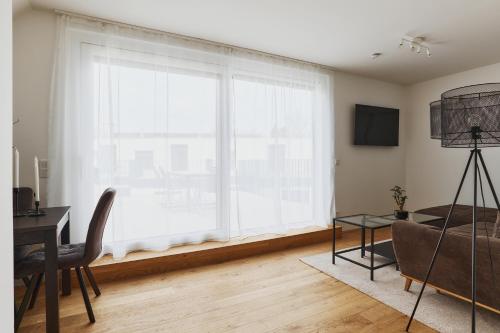 a living room with a large window and a table at Symphony Apartments Vienna - Garden, Terrace and Grill in Vienna