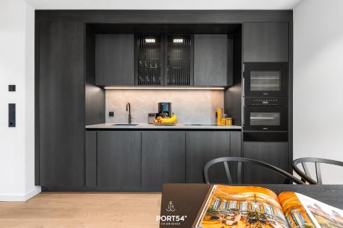 a kitchen with black cabinets and a table at Brooklyn Bridge Suite List auf Sylt in List