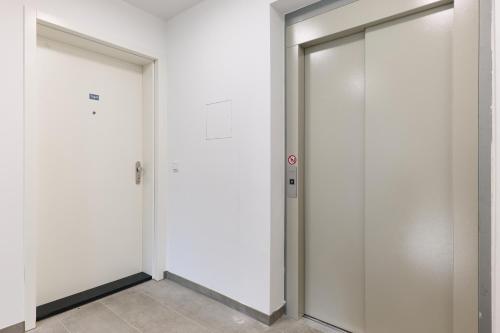 two white elevator doors in a white wall at Symphony Apartments Vienna - Garden, Terrace and Grill in Vienna