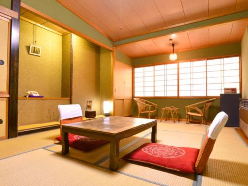 a living room with a table and chairs in it at 咲花温泉 ホテル丸松 in Gosen