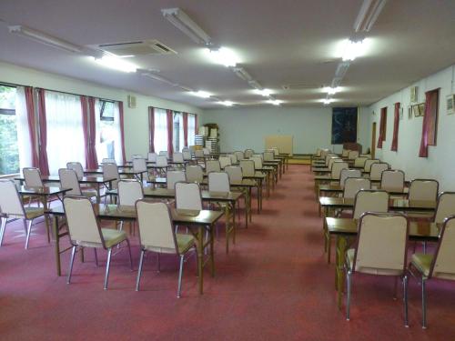 an empty room with tables and chairs and windows at 咲花温泉 ホテル丸松 in Gosen