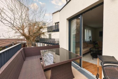 a balcony with a glass table and a couch at Symphony Apartments Vienna - Garden, Terrace and Grill in Vienna