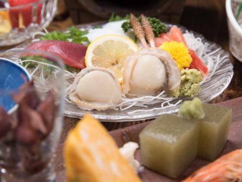 a plate of food with meat and vegetables on a table at 咲花温泉 ホテル丸松 in Gosen