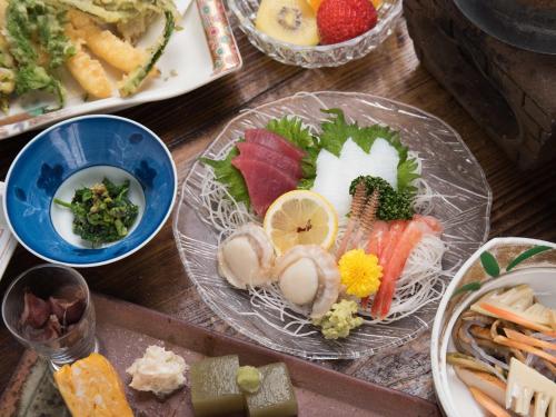 a wooden table with plates of food on it at 咲花温泉 ホテル丸松 in Gosen