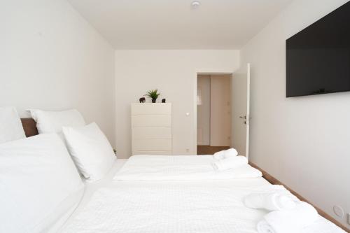 two white beds in a room with a tv at Symphony Apartments Vienna - Garden, Terrace and Grill in Vienna