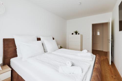 a bedroom with two beds with white sheets and towels at Symphony Apartments Vienna - Garden, Terrace and Grill in Vienna