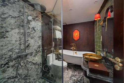 a bathroom with a shower and a tub and a sink at Indochine Grand Lan Ha Bay in Ha Long