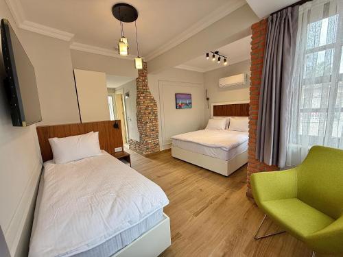 a bedroom with two beds and a green chair at Adria Inn in Antalya