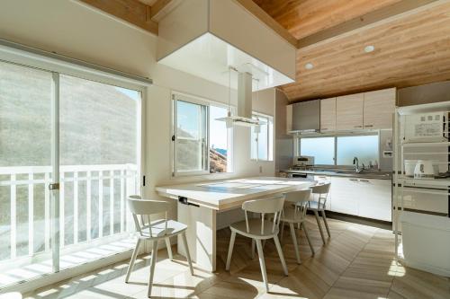 a kitchen with a table and chairs and a large window at COCO VILLA 大室山 -Izu Omuroyama- in Futo