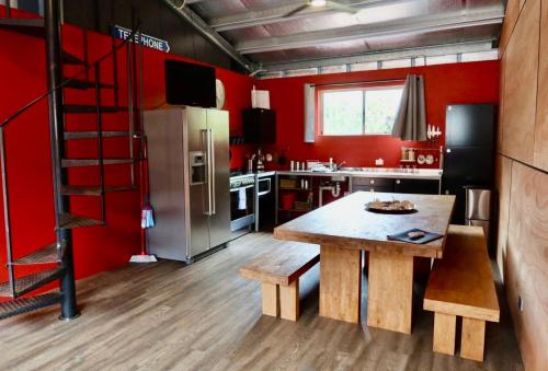 a kitchen with a wooden table and red walls at Unique Australian Shed Style House in Dunsborough
