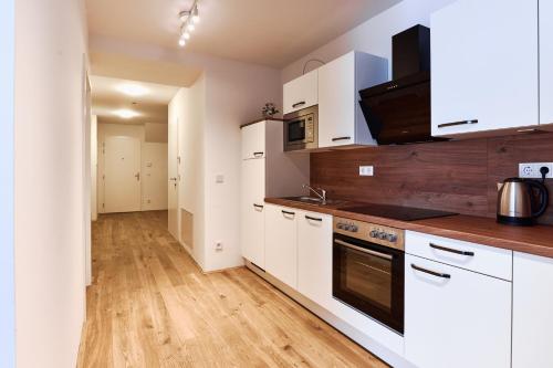 a kitchen with white cabinets and a wooden floor at Symphony Apartments Vienna - Garden, Terrace and Grill in Vienna