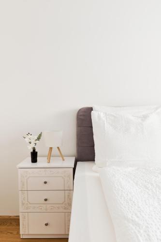a bedroom with a white bed and a nightstand at Symphony Apartments Vienna - Garden, Terrace and Grill in Vienna