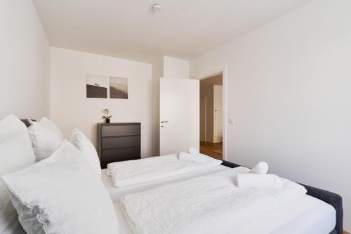 two beds in a bedroom with white walls and white pillows at Symphony Apartments Vienna - Garden, Terrace and Grill in Vienna