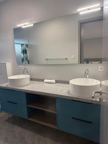 a bathroom with two sinks and a large mirror at The Cave Beach House in Lagun