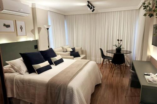 a bedroom with a bed and a table and a couch at Charmoso, moderno e central! 11 in Poços de Caldas