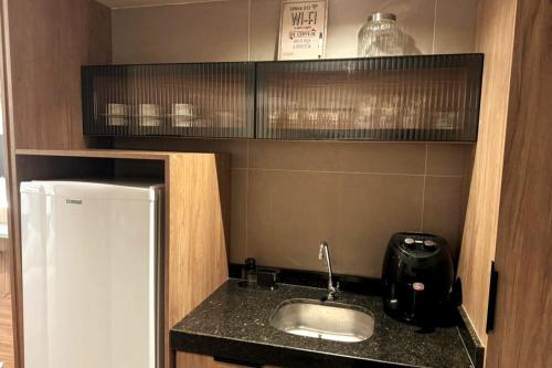 a small kitchen with a sink and a refrigerator at Charmoso, moderno e central! 11 in Poços de Caldas