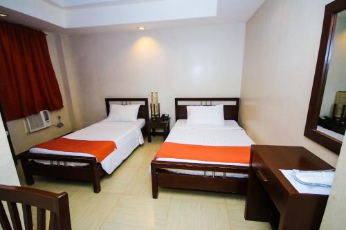 a hotel room with two beds and a desk at Roxas Midtown Hotel in Roxas City