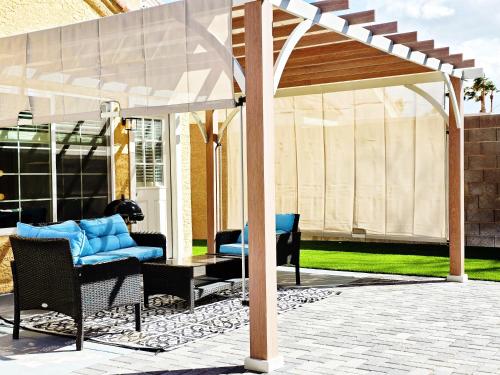 a pergola with a blue couch and chairs on a patio at Near the Strip, Smart TVs, WiFi, private garage and backyard in Las Vegas
